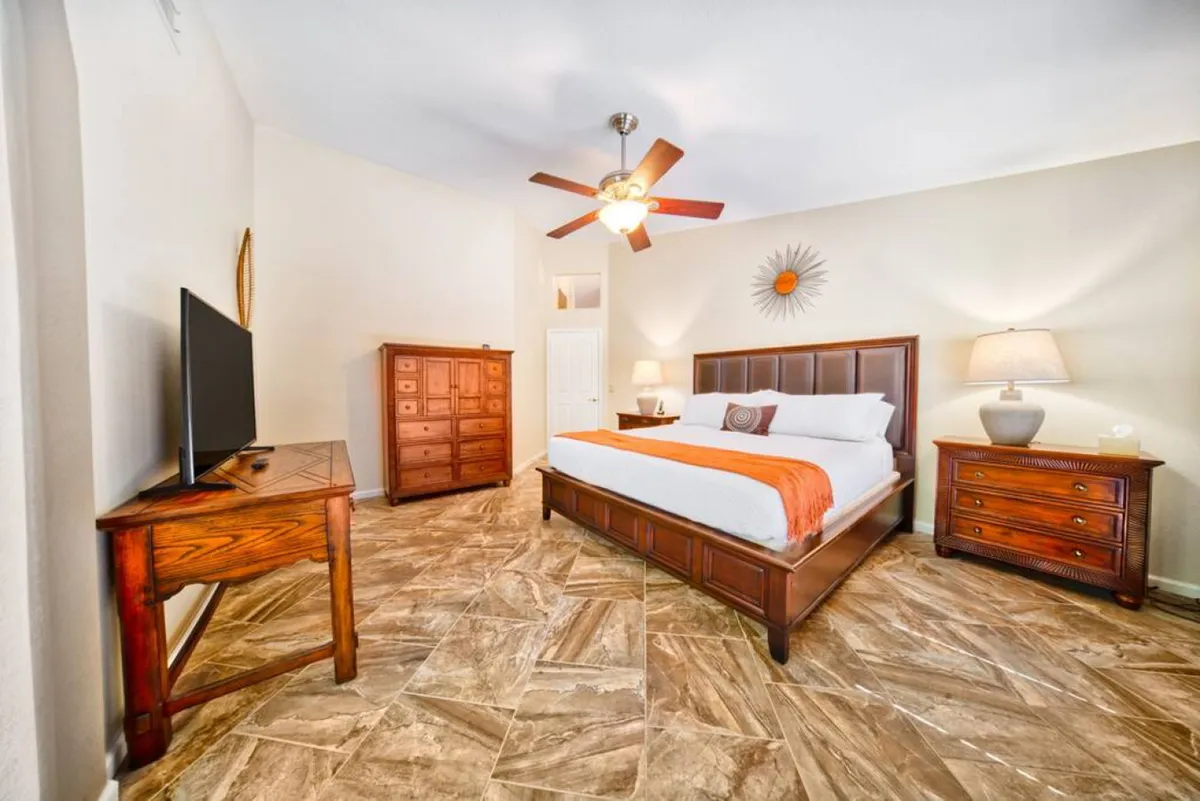 A comfortable bedroom is shown here, complete with a bed, dresser, TV, lamp, and a ceiling fan. The layout emphasizes both relaxation and functionality, highlighting a space to unwind, read, or enjoy some entertainment in privacy.