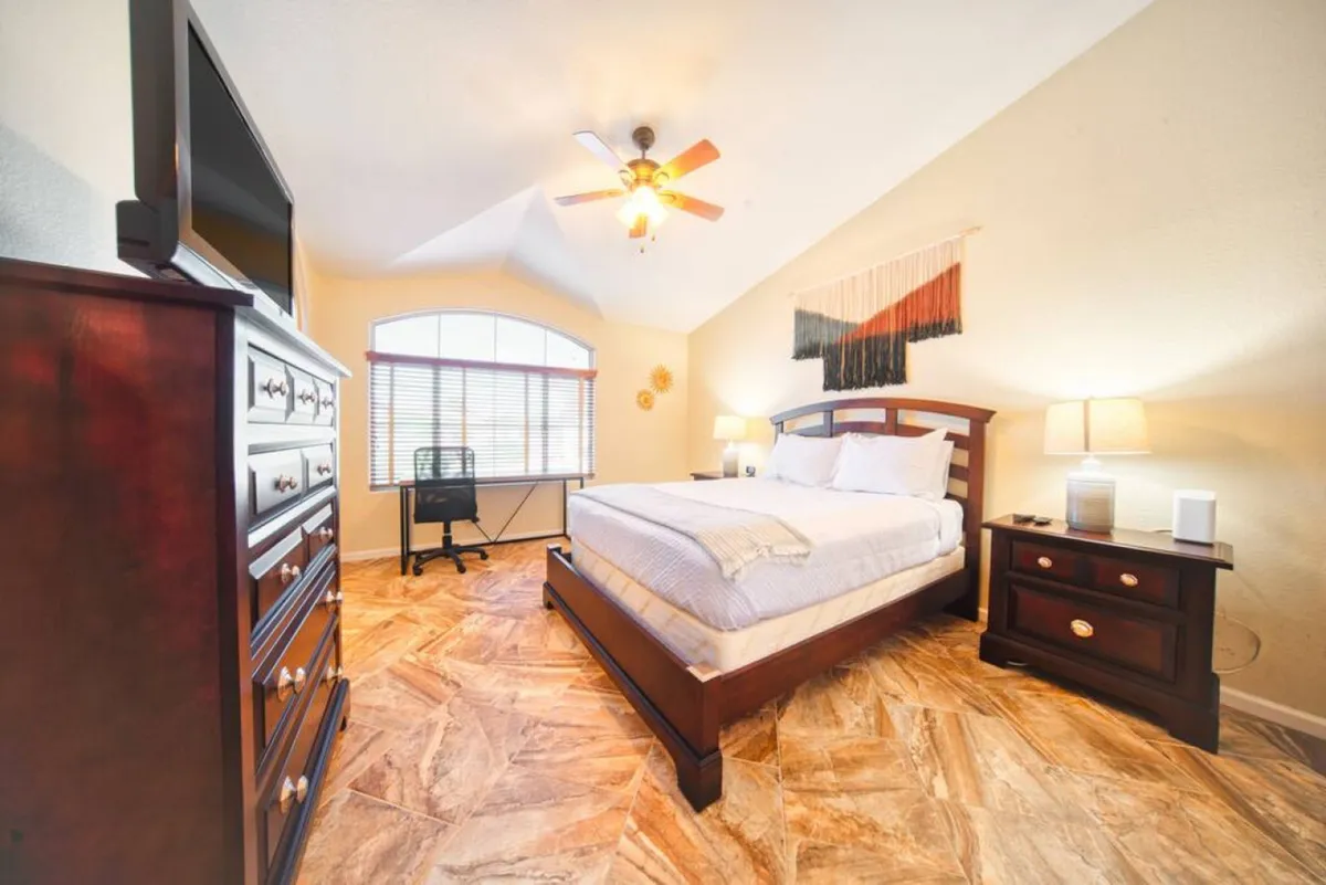 This image features a calm bedroom with a neatly made bed, a window that lets in plenty of natural light, a nightstand, and a dresser. The overall palette and arrangement evoke a sense of tranquility and comfort—ideal for peaceful nights and serene mornings.